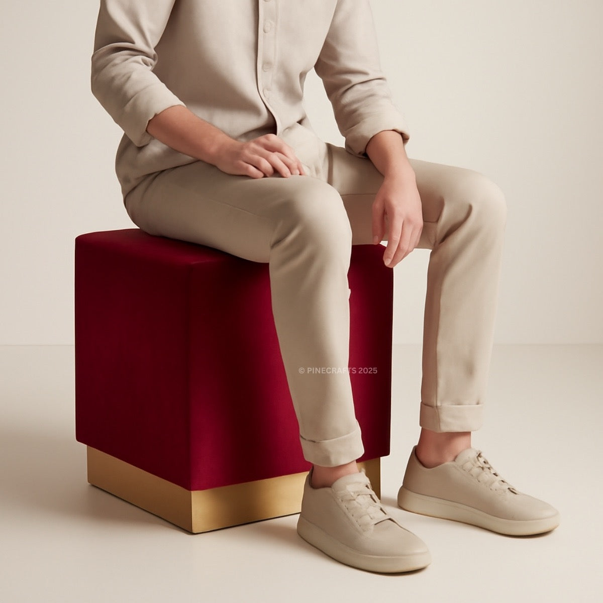 Person sitting on a red and gold cube with beige pants and shoes.